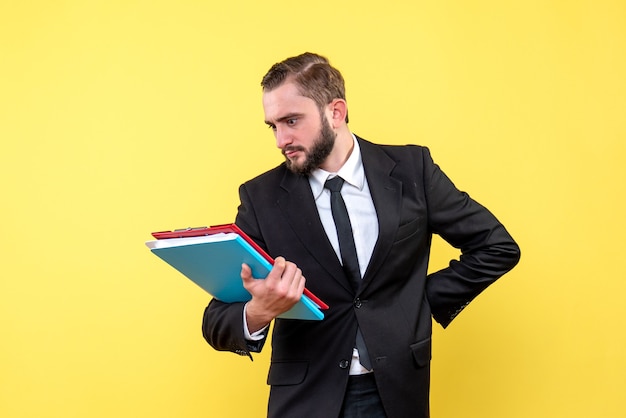 Free photo front view of young man businessman reading carefully documents on red clipboard on yellow