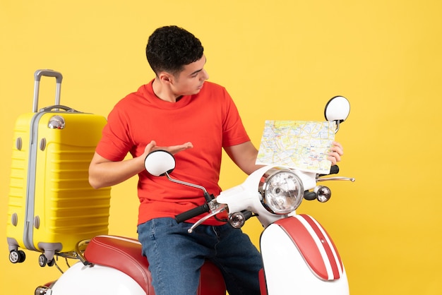 Front view young man in casual clothes on moped looking at travel map