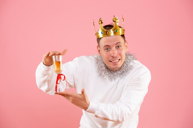 Front view of young man celebrating christmas with drink on pink wall