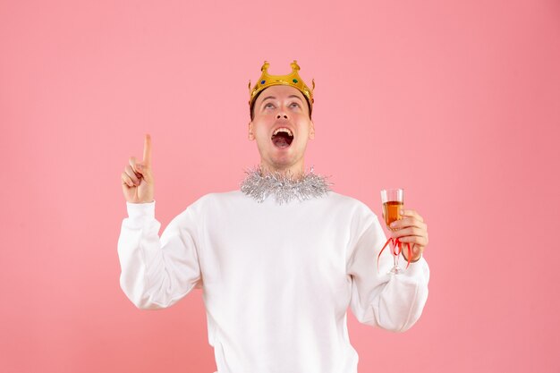 Front view of young man celebrating christmas with drink on pink wall