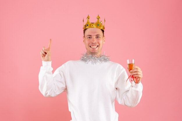 Front view of young man celebrating christmas with drink on the pink wall