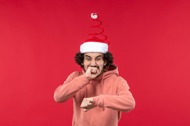 Front view of young man checking time with sorry face on red wall