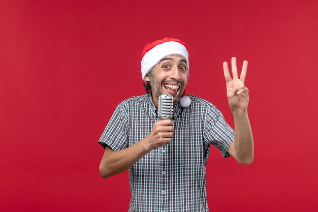 Front view young man counting showing number on red background