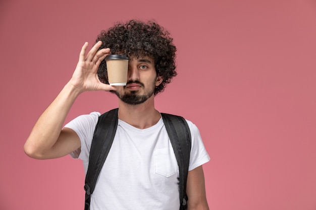 Front view young man covering his eye with paper coffee cup