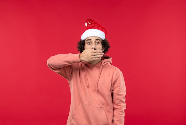 Free photo front view of young man covering his mouth on red wall