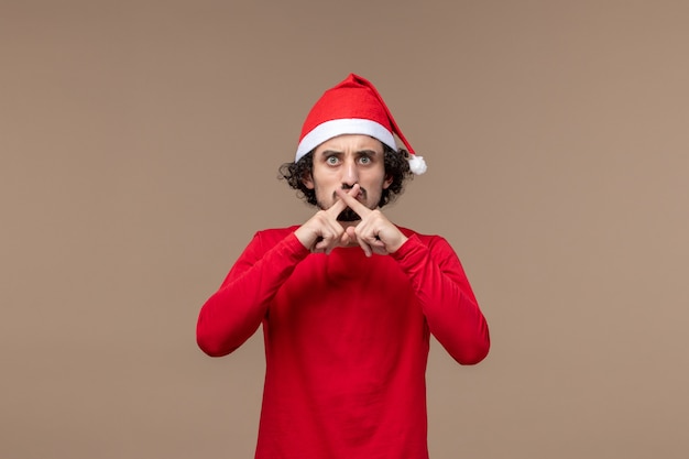 Front view young man crossing fingers on a brown background holiday emotion christmas