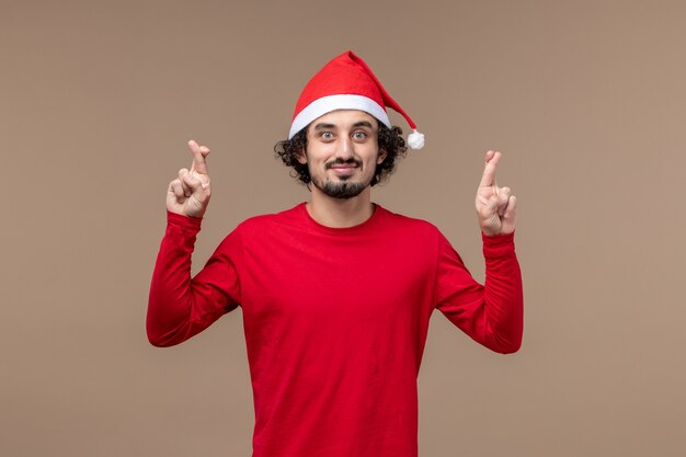 正面図茶色の背景に指を交差する若い男クリスマス感情休日