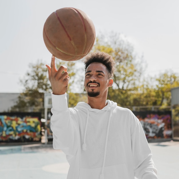 Foto gratuita giovane di vista frontale che fa i trucchi con una pallacanestro