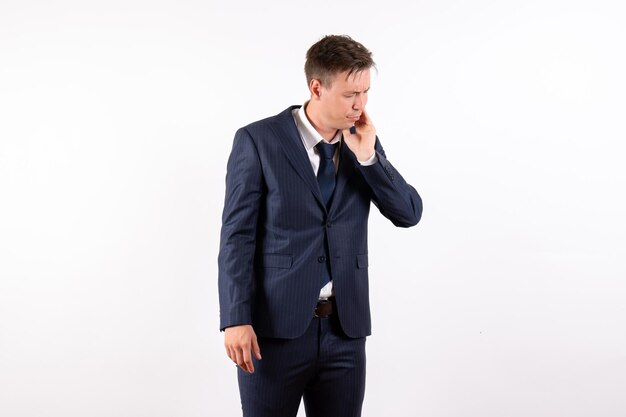 Front view young man in elegant classic suit having toothache on white background