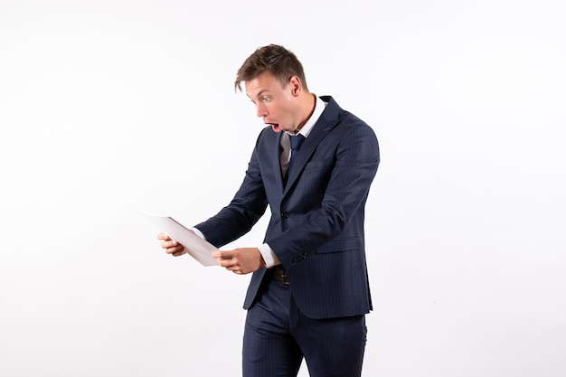 Front view young man in elegant classic suit holding different documents on a white background