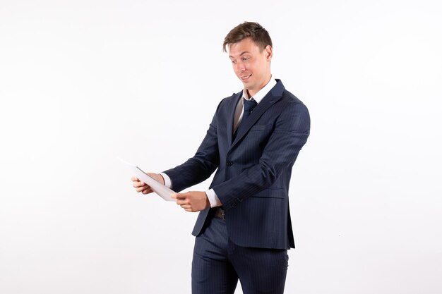 Front view young man in elegant classic suit holding different documents on white background