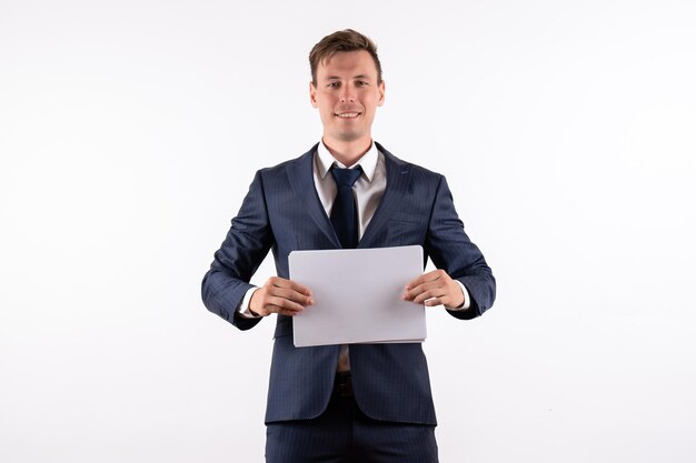 Front view young man in elegant classic suit holding documents on a white background