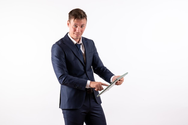 Front view young man in elegant classic suit holding huge calculator on the white background