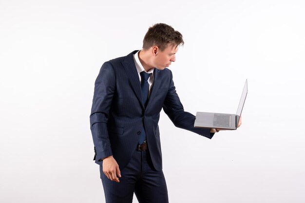 Front view young man in elegant classic suit holding laptop on a white background