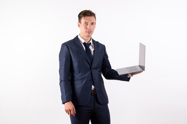 Front view young man in elegant classic suit holding laptop on white background