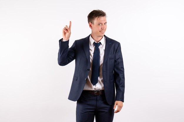 Front view young man in elegant classic suit raising his finger on white background
