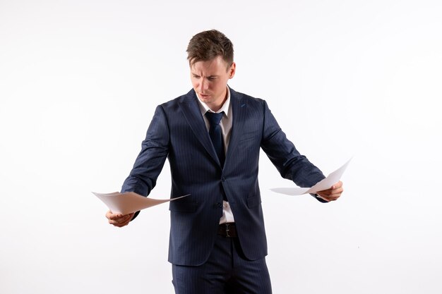 Front view young man in elegant classic suit reading documents on white background