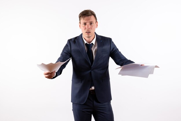 Front view young man in elegant classic suit reading documents on white background