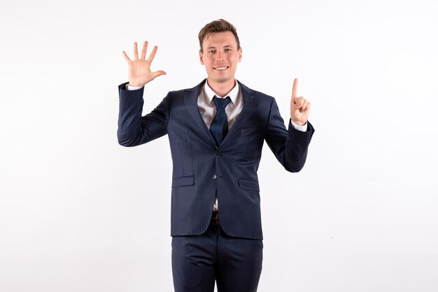 Front view young man in elegant classic suit showing his hand and finger on white background