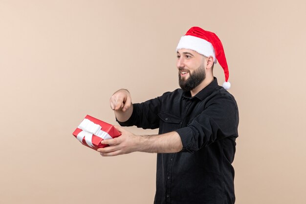 Front view of young man giving present to someone on a pink wall