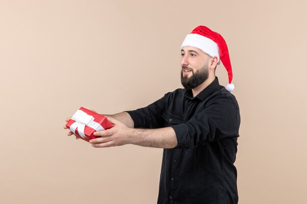 Front view of young man giving present to someone on pink wall