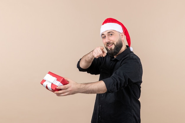 Front view of young man giving present to someone on the pink wall