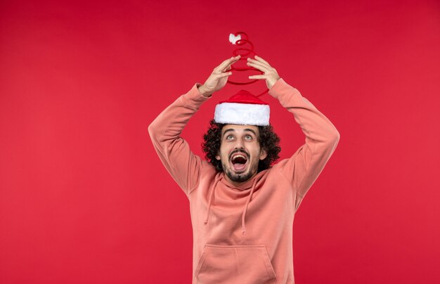 Front view of young man happily rejoicing on red wall