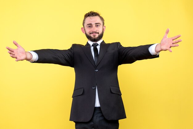 Front view of young man happy businessman wants to hug on yellow