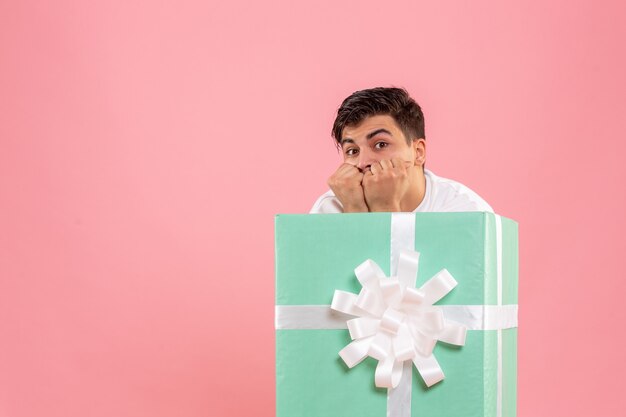 Free photo front view of young man hiding inside present scared on pink wall