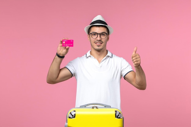 분홍색 벽에 은행 카드를 들고 있는 청년의 전면 모습