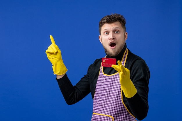 Free photo front view of young man holding card pointing at ceiling on blue wall