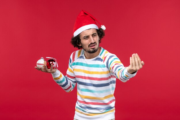 Front view young man holding christmas tree toys on red wall holiday red human new year