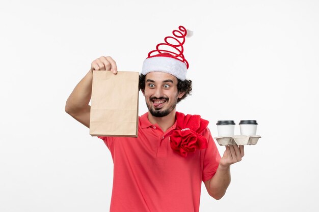 Front view of young man holding delivery coffee on a white wall