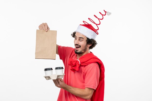 Front view of young man holding delivery coffee on the white wall