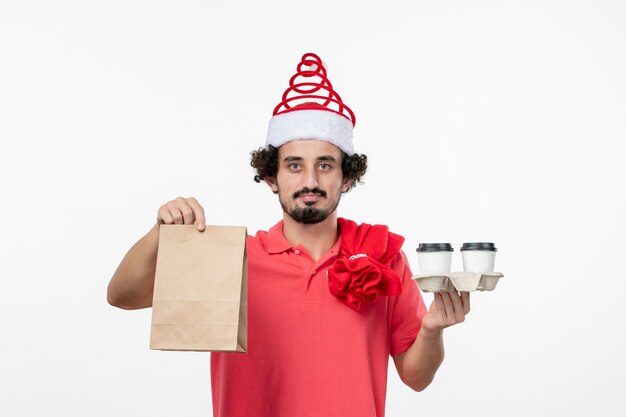 Front view of young man holding delivery coffee on white wall