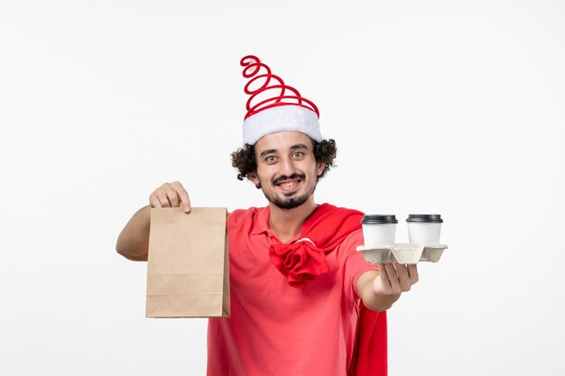 Front view of young man holding delivery coffee on white wall