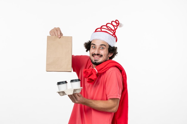 Front view of young man holding delivery coffee on white wall