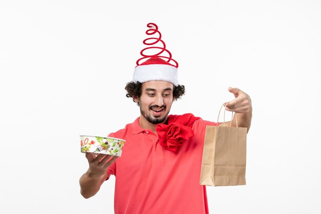 Front view of young man holding delivery food on a white wall