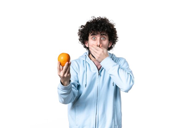 Front view young man holding fresh orange on white background health body muscle losing slimming fruit measuring weight