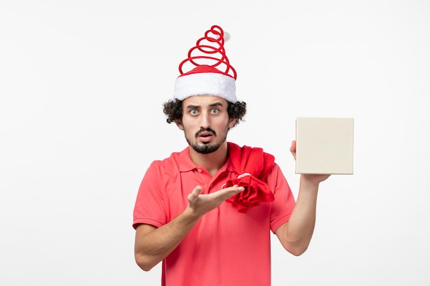 Front view of young man holding holiday present on a white wall