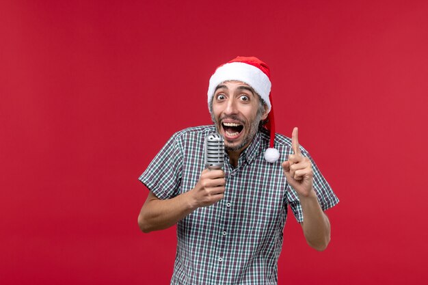 Front view young man holding mic on red wall emotion holidays singer music