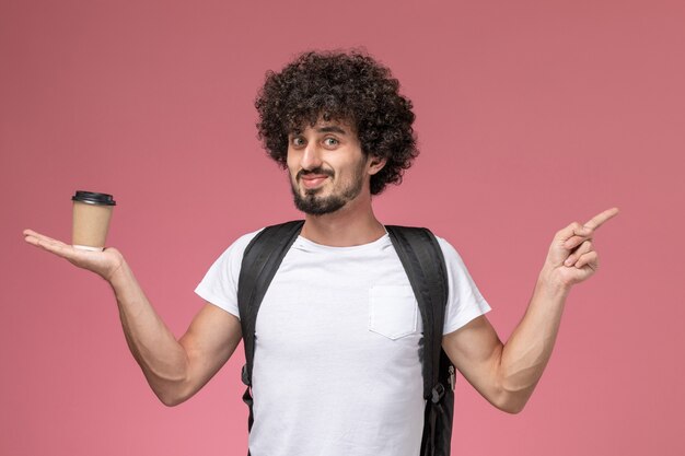 Front view young man holding paper coffee cup and pointing out other direction