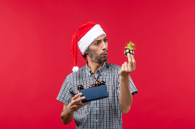 Front view of young man holding plastic toys on red