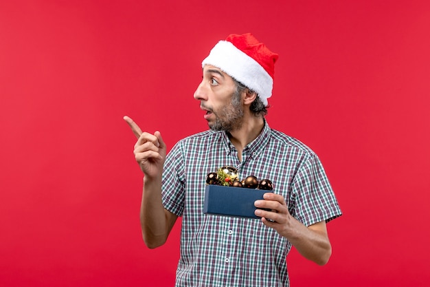 Front view of young man holding plastic toys on red