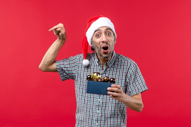 Front view of young man holding plastic toys on red