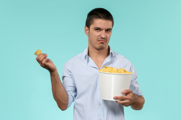 青い壁の孤独なリモート男性映画館で映画を見ながらジャガイモのcipsを保持している正面図若い男