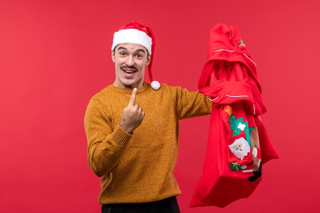 Free photo front view of young man holding present bag on a red wall