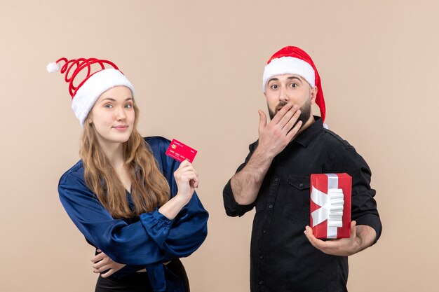 Front view of young man holding present with woman whos holding bank card on the pink wall