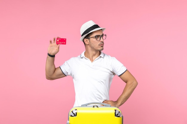 분홍색 벽에 빨간 은행 카드를 들고 있는 젊은 남자의 전면 모습