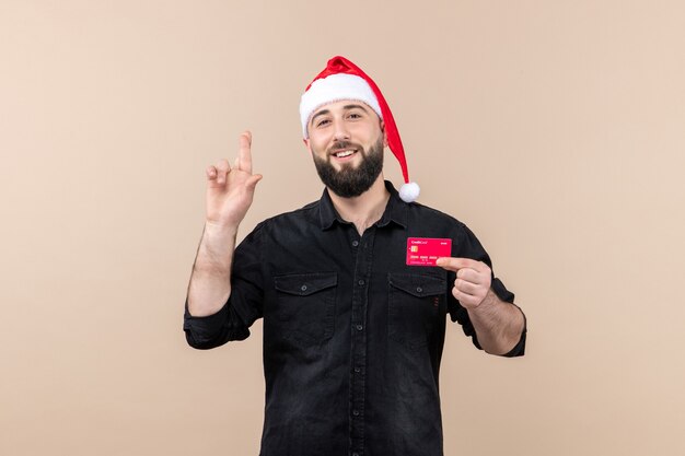 Front view of young man holding red bank card smiling on pink wall